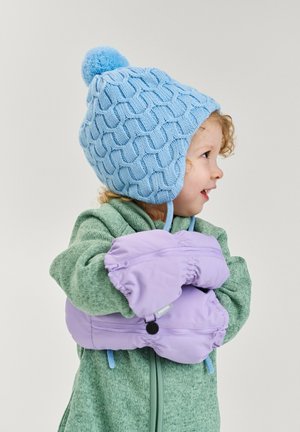 Bonnet tricoté bleu clair avec un pompon, motif texturé ; veste en polaire verte, tenant des moufles lavande avec des poignets élastiques.