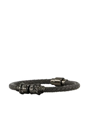 Zwarte gevlochten leren armband met twee kleine metalen schedelbedels en een magnetische sluiting, afgebeeld op een witte achtergrond.