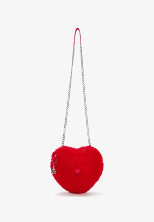 Bolso en forma de corazón rojo con textura suave y esponjosa, cadena de plata como strap y un charm adjunto. Presenta un detalle destacado de pom-pom.