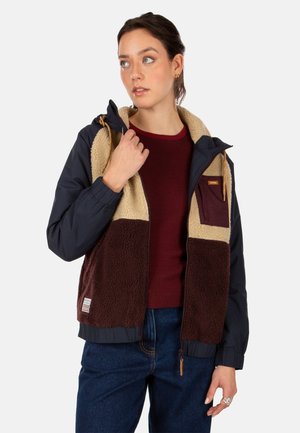 Fleece-lined jacket featuring a navy body, brown and beige color blocks, zip pockets, and adjustable drawstring hood. Fabric appears soft and textured.