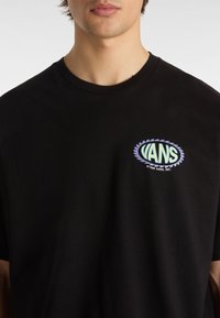 Black cotton t-shirt featuring a multicolored "VANS" logo in an oval shape on the chest. Classic crew neckline and short sleeves.