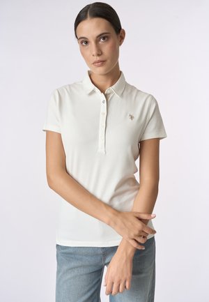 Polo bianco con colletto, maniche corte e patta con tre bottoni. Presenta un piccolo logo ricamato sul petto. Tessuto liscio.