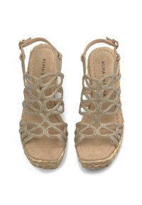 Sandali wedge beige con design intagliato intricato e dettagli metallici, dotati di un suola in espadrilla testurizzata e di una fascia alla caviglia regolabile.