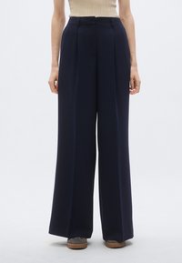 Navy wide-leg trousers with a high waist and front pleats. Smooth, lightweight fabric with a tailored fit. Minimalistic design.