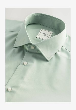 Light green shirt featuring a structured collar, white buttons, and fine texture. Label reads "NEXT TAILORING" in a square design.