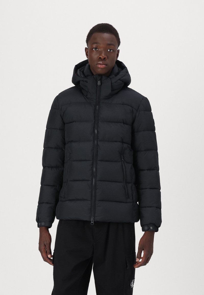 Sort puffer jakke med hætte, med kviltet design, lynlås foran og sidelommer, lavet af kuldebestandigt materiale.