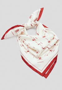 Jedwabny szalik z kremowym tłem i czerwonymi wzorami oraz tekstem, zakończony czerwoną ramką. Związany na środku dla stylizacji.