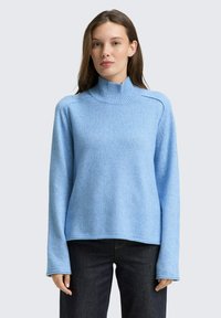 Hellblauer Pullover aus weichem Strickmaterial, mit einem hohen gerippten Rundhalsausschnitt, langen Ärmeln und einem lockeren Schnitt mit Seitennähten.