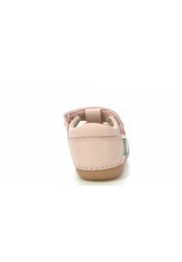 Sandalia de cuero rosa con forma redondeada, talón abierto, correa ajustable y forro interior suave. Presenta una suela cosida y una pequeña etiqueta de la marca.
