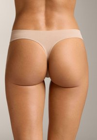 Bež modrček iz gladkega blaga z minimalističnim dizajnom, nizkim pasom in brezšivnimi robovi.