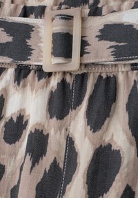 Beige og sort leopardprint stof med matchende bælte og gennemsigtig rektangulær spænde.