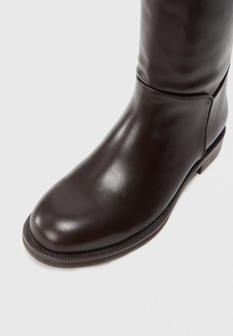 Braune Lederstiefel bis zum Knie mit runder Zehenform, glatter Textur, minimaler Naht und niedrigem Absatz. Verfügt über eine elegante, körpernahe Silhouette.