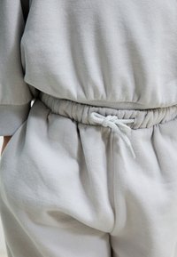 Heledast hallidest mugav riietus, millel on lõdvestunud lõige, elastne vöökoht paelaga ja pehme, tekstureeritud kangas.