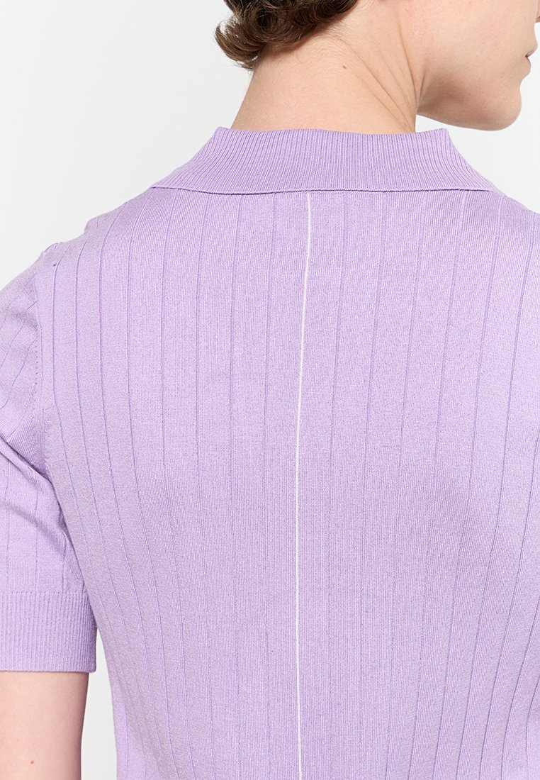 Lavendelfarbenes, gerippter Strickoberteil mit kurzem Kragen, versehen mit einer weißen vertikalen Naht auf der Rückseite. Glatte Textur und figurbetontes Design.