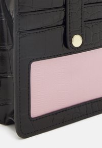 Black faux crocodile leather pouch with a pink fabric panel and gold snap closure. Textured surface with visible stitching detail.