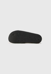 Talpa de pantof din cauciuc negru, cu o suprafață texturată, dotată cu crampoane circulare și un margine netedă. Marca include logo-ul mărcii și informații despre model.