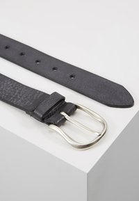 Black leather belt with a textured finish, featuring a silver metal buckle and five adjustment holes along its length.