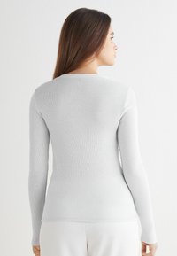 Szary prążkowany top z długim rękawem, okrągłym dekoltem, dopasowanym krojem i gładką fakturą. Brak widocznych wzorów lub akcentów.