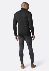 Czarny longsleeve z wysokim kołnierzem i szwami płaskimi, w połączeniu z szarymi dopasowanymi legginsami, wykonanymi z miękkiego, elastycznego materiału.