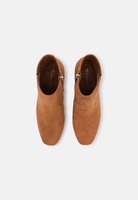 Bottines en daim marron à texture lisse, bout amande, fermetures éclair latérales et design simple. La taille 37 est visible à l'intérieur.