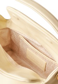 Beige leather handbag interior with a smooth texture, featuring a patterned lining and a labeled pocket. Double handles are visible.