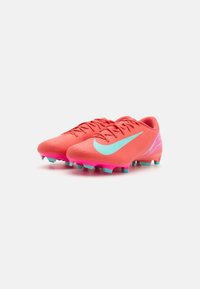Bright coral soccer cleats with a textured upper, featuring a large aqua swoosh, pink accents on the sole, and multi-colored studs.