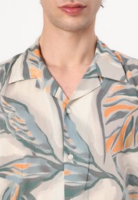 Κοντομάνικο πουκάμισο από ελαφρύ, υφασμάτινο υλικό, με λουλουδάτο σχέδιο σε τιρκουάζ, πορτοκαλί και γκρι, κουμπιά μπροστά και επίπεδο γιακά.