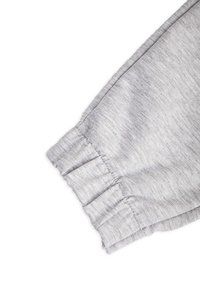 Szary bawełniany materiał o miękkiej fakturze, z marszczonymi mankietami i złożonym brzegiem, charakteryzujący się casualowym stylem, idealnym do wygodnego noszenia.