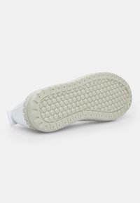 Suela de zapato blanca con un diseño texturizado de patrones circulares, hecha de goma flexible para mayor agarre y durabilidad.