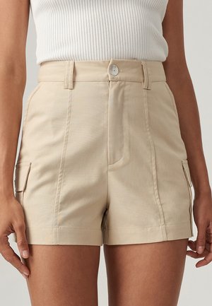 Beige shorts med høj talje, der har for- og sidelommer, knaplukning og en glat tekstur.