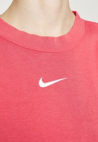 Röd bomullst-shirt med rund halsringning och en vit Nike-logotyp på bröstet. Tyget har en slät yta och är avslappnat i stilen.