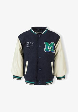 Veste varsity en polyester navy avec des manches en cuir crème, lettre "M" brodée en vert et bleu, bords côtes aux poignets et deux poches avant.