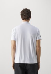 Weißes Polohemd aus leichtem Stoff, mit klassischem Kragen und kurzen Ärmeln, ausgestattet mit feinem Strukturmuster und ohne sichtbare Logos.