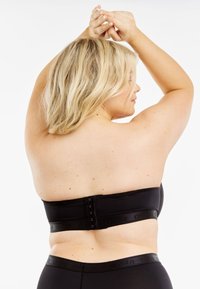 Svart bandeau topp utan axelband med en slät textur, med en hakhängare i ryggen och ett elastiskt band med varumärke.