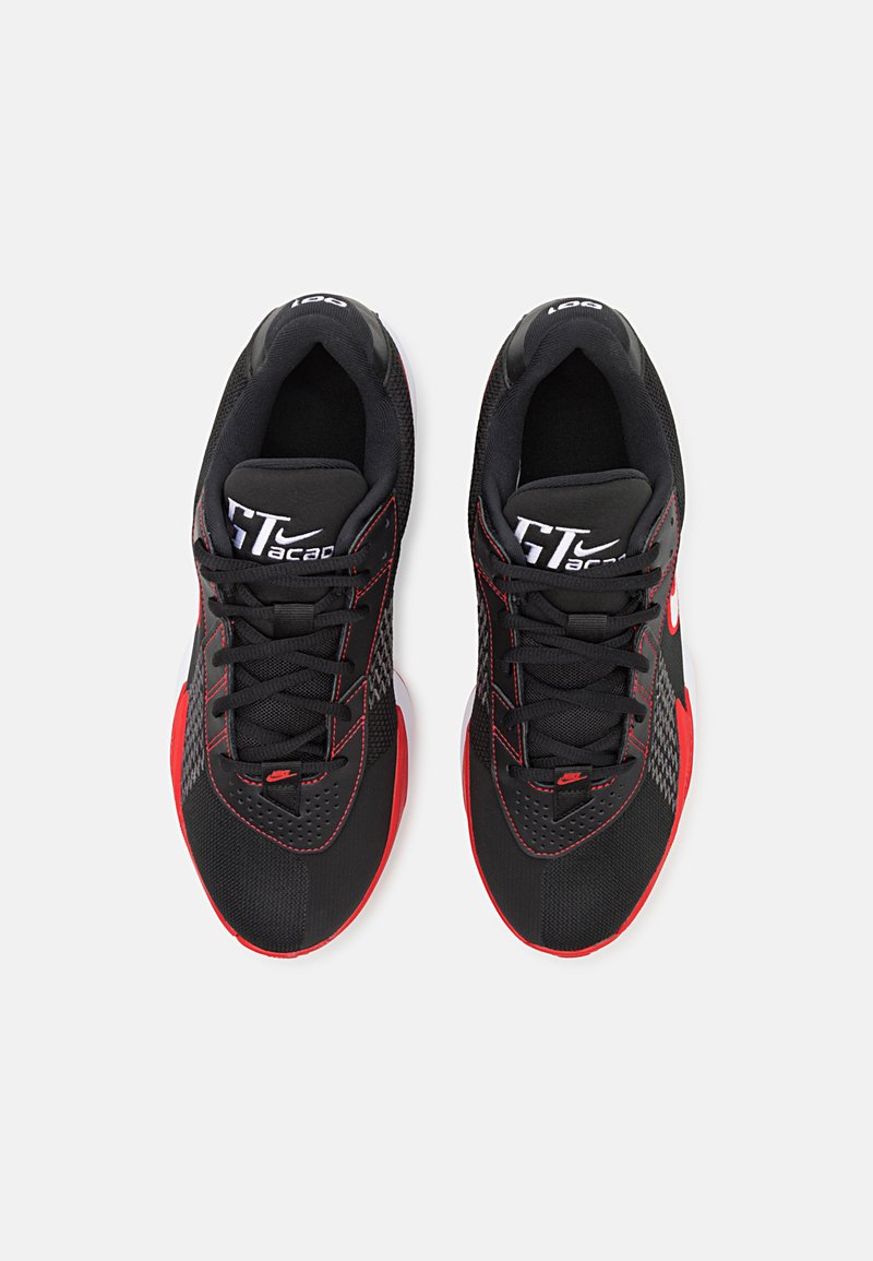 Zapatillas deportivas negras con acentos rojos, material de malla y diseño texturizado. Presentan cordones y un logo en la lengüeta. Punta redondeada y suela acolchada.