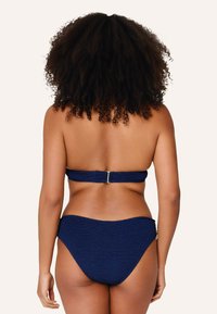 Námořnická modrá bikini sada se strukturovaným bandeau topem se zlatou sponou a spodními kalhotkami s mírným krytím a bezšvovými okraji.