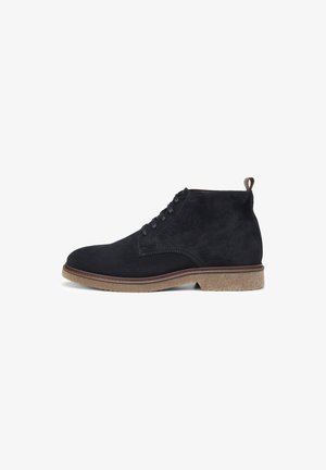 Schwarze Wildleder-Ankle-Boots mit runder Zehenform, schnürbarem Vorderteil und hellbrauner Gummisohle; verfügen über einen kleinen Absatz und eine Schlaufe an der Rückseite.