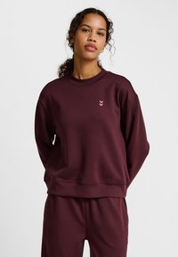 Bordeaux sweatshirt met een ronde hals, lange mouwen en een roze chevronlogo op de borst. Zachte textuur en een ontspannen pasvorm.