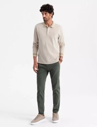 Krémové polo tričko s dlouhým rukávem, žebrovaným límečkem a manžetami, kombinované se zelenými slim-fit kalhotami a světle krémovými teniskami. Minimalistický design.