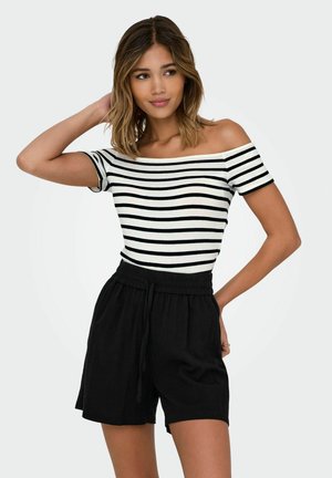 Sort og hvid stribet off-the-shoulder top parret med sorte shorts med snøre, der har en afslappet pasform og blød stoftekstur.