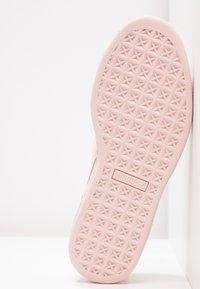 Světle růžová gumová podrážka s texturovaným geometrickým vzorem a značkovou insignií. Hladké hrany a zaoblený podpatek pro pohodlí.