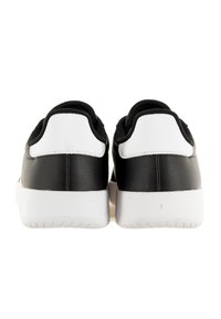 Baskets noires avec une finition en cuir lisse, des accents de talon blancs contrastants et des semelles texturées. Présente un col rembourré et un design minimaliste.