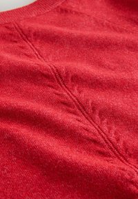Red, knitted fabric with a subtle texture. Features a center seam with decorative stitching along the edges. Soft, medium weight material.