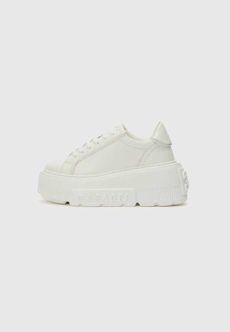 White platform sneakers made of smooth leather, featuring rounded toe, thick sole with textured pattern, and subtle branding on the side.