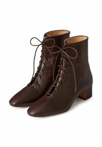 Brązowe skórzane botki za kostkę z zaostrzonym noskiem, delikatnym wiązaniem z przodu oraz niskim obcasem na klocku. Gładka faktura, minimalistyczny design.