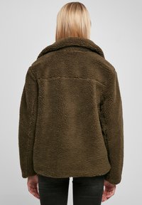 Bruine, gestructureerde fleecejack met een wijde kraag, een boxy pasvorm en een gladde binnenlaag, met een achternaad en verborgen zakken.