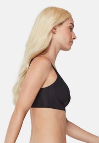 Bralette negro sin costuras con tirantes finos, tela suave, diseño minimalista y acabado liso. Adecuado para uso casual o para superponer.