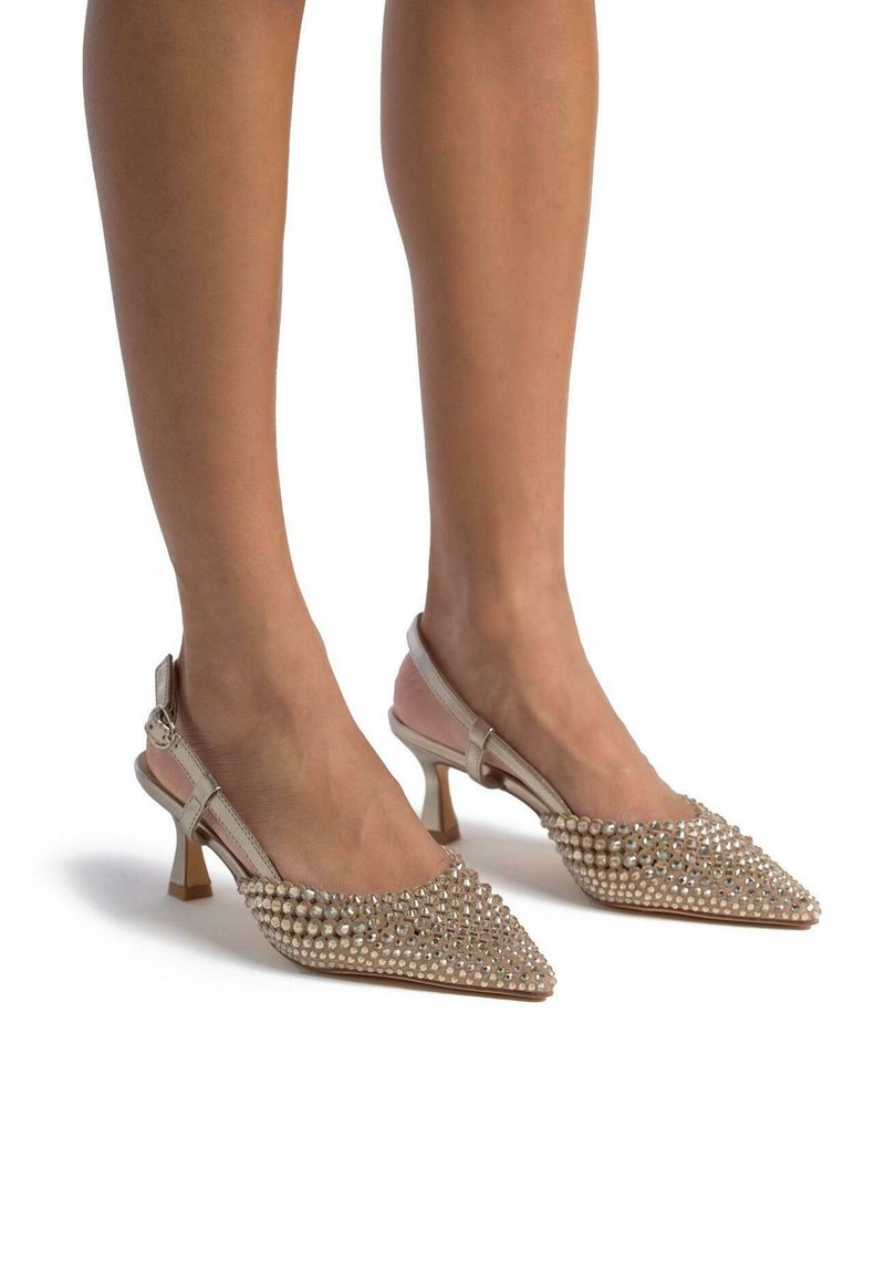 Escarpins beige à bride arrière avec bouts pointus, couverts de strass étincelants, dotés d'un petit talon kitten et d'une bride de cheville ajustable.