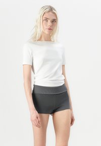 Hvit kortermet topp med rund hals, sammen med mørkegrå striped shorts med en bred midje. Glatt tekstur, avslappet passform.