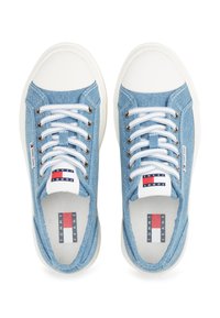 Helle blaue Denim-Sneaker mit weißen Gummisohlen, ausgestattet mit weißen Schnürsenkeln, silbernen Ösen und einem Zungenlabel mit rot-, weiß- und blau-akzenten.